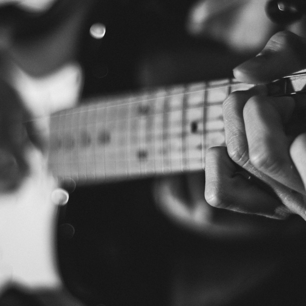 grayscale photo of person playing guitar