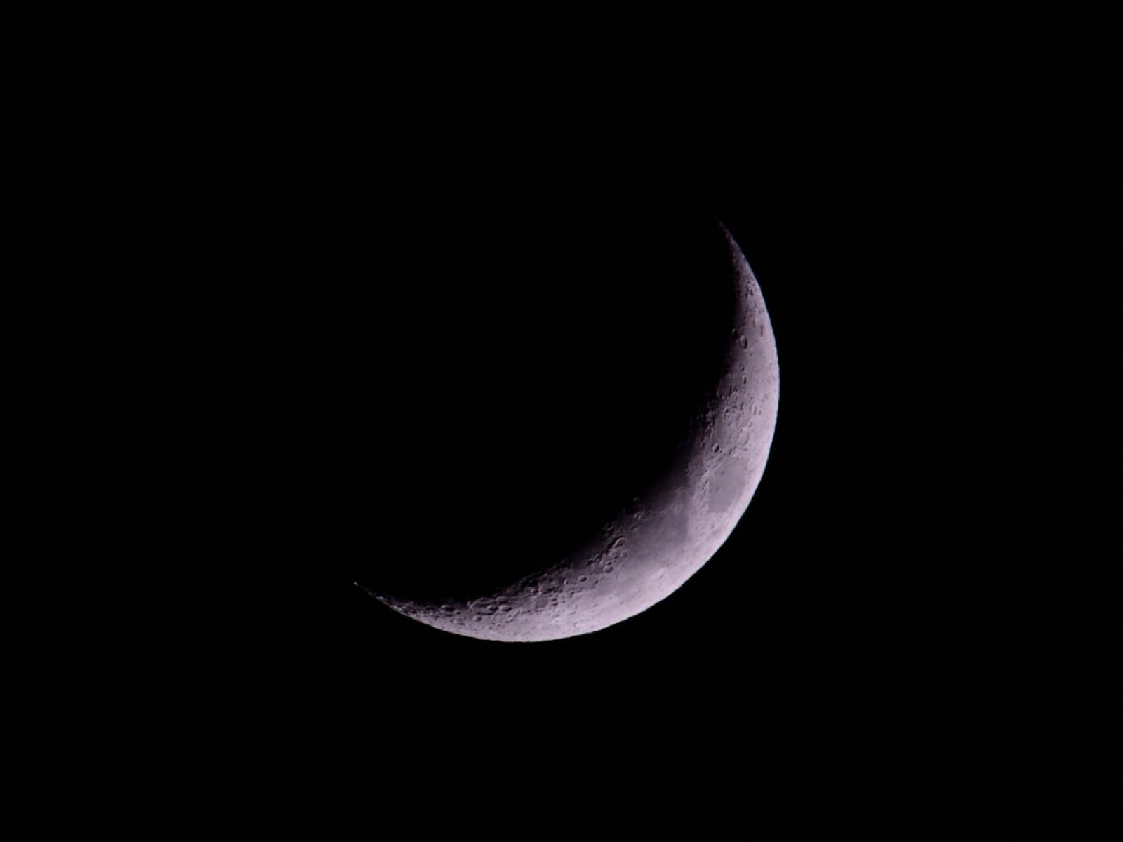 A crescent moon shines brightly in the night sky.